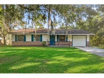 Charming single-story home with a brick facade, blue shutters, manicured lawn, and mature trees at 4805 Jay Dr, St Cloud, FL 34772
