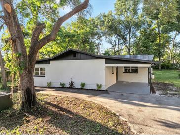 Charming home with a white exterior, black roof, and a covered carport at 7043 Carlene Dr, Orlando, FL 32835