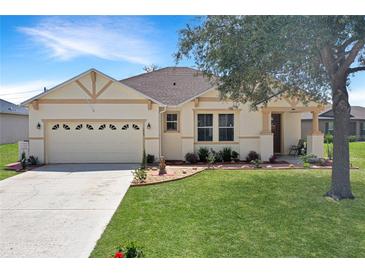 Inviting one-story home featuring a well-manicured lawn, two-car garage, and charming front porch at 1405 Hillsborough Way, Kissimmee, FL 34759
