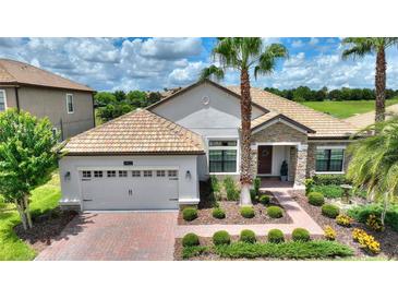 Charming single Gathering home featuring a beautiful tile roof, manicured landscaping, and a two-car garage at 1452 Mickelson Ct, Davenport, FL 33896