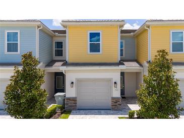 Charming townhouse with a one-car garage, colorful facade, and well-maintained landscaping, creating an inviting curb appeal at 7920 Draw St, Reunion, FL 34747