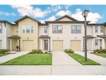 New townhomes featuring attached garages, well-manicured lawns and sidewalks on a beautiful, sunny day at 816 Longboat Dr, Davenport, FL 33896