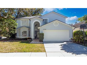 Charming two-story home with attached two-car garage, manicured lawn and mature trees at 13129 Cog Hill Way, Orlando, FL 32828