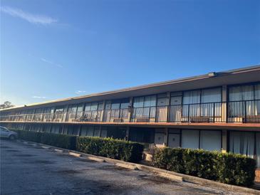 Low angle shot of a multi-unit exterior with a long row of rooms, black railing, and partial parking lot at 7900 S Orange Blossom Trl # 2136, Orlando, FL 32809