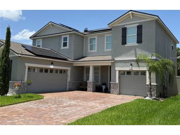 Charming two-story home featuring a brick driveway, two-car garage, and solar panels at 3252 Jackson Bluff Way, Clermont, FL 34711