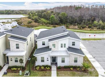 Modern two-story home featuring stone accents, well-kept landscaping, and a view of the nearby lake at 2901 Protagonist St, Kissimmee, FL 34746