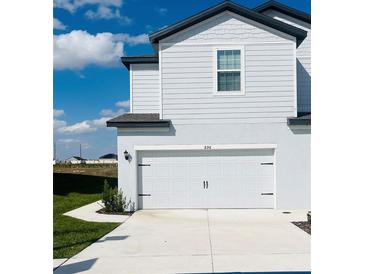 Charming two-story home featuring light blue siding and a white garage door at 896 Poppy Ln, Dundee, FL 33838