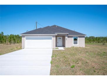 New single-Gathering home with a gray roof, white garage, and long concrete driveway at 2700 Laguna Dr, Indian Lake Estates, FL 33855