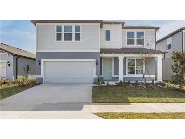 Two-story home with gray siding, a light green door, and a two-car garage at 4390 Sw 84Th Street Rd, Ocala, FL 34476