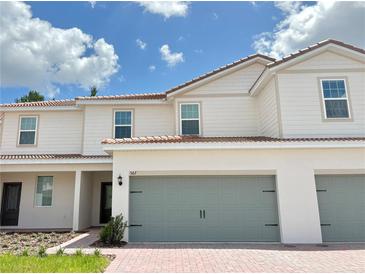 Charming two-story home featuring a gray two-car garage, a red tile roof and a brick driveway at 567 Bay Leaf Dr, Poinciana, FL 34759
