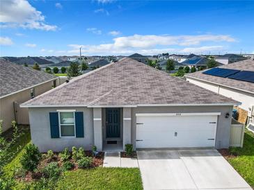 One-story home with gray exterior, two-car garage, and landscaped front yard at 408 Boardwalk Ave, Haines City, FL 33844