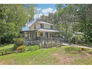 Charming two-story home featuring a large porch and lush, mature landscaping around the property at 3603 Cr 626N, Bushnell, FL 33513