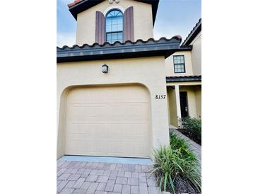 Inviting two story townhome with a tan stucco exterior, decorative shutters, and a two car garage at 8157 Roseville Blvd, Davenport, FL 33896