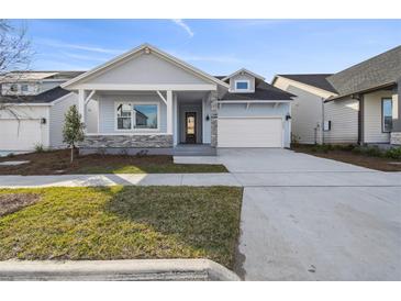 New single-story home with light blue siding, stone accents, and a two-car garage at 3068 Bootlace Way, St Cloud, FL 34771