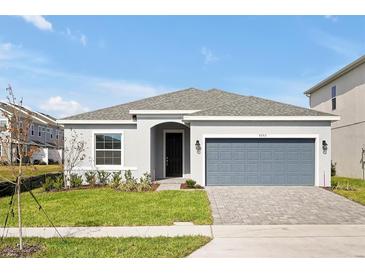 New one-story home with gray siding, gray garage door, and landscaped lawn at 5753 Wallis Ln, St Cloud, FL 34771