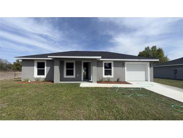 Charming gray home with a well-manicured lawn and a freshly sealed driveway at 13371 Sw 112Th Pl, Dunnellon, FL 34432