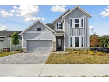 Two-story house with gray siding, stone accents, and a paved driveway at 6086 Sacred Oak Ave, Mount Dora, FL 32757