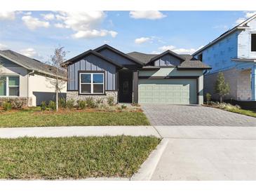 Two-story home with gray and green exterior, stone accents, and a paved driveway at 6075 Sacred Oak Ave, Mount Dora, FL 32757