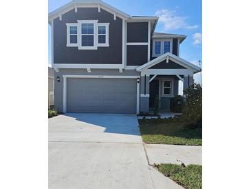 Charming two-story home with gray siding, a two-car garage, and a well-manicured lawn under a bright blue sky at 6652 Great Bear Dr, Lakeland, FL 33805