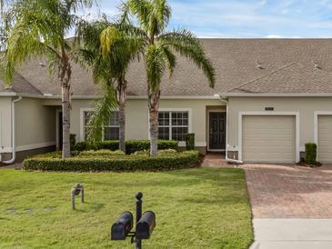 Charming townhome with a manicured lawn, palm trees, and brick paver driveway, offering curb appeal at 3825 Quaint Ln # C, Clermont, FL 34711