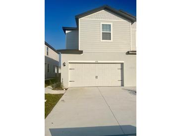 Two-story home featuring a large garage with black hardware, a concrete driveway, and neutral colored siding at 775 Poppy Ln, Dundee, FL 33838