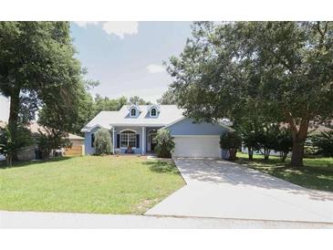 Charming single-story home with manicured lawn, mature trees, and a welcoming two-car garage at 2819 Ne 25Th St, Ocala, FL 34470