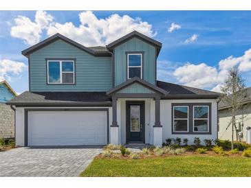 Charming two-story home featuring a blue exterior, well-manicured lawn, and an attached two-car garage at 6074 Sacred Oak Ave, Mount Dora, FL 32757
