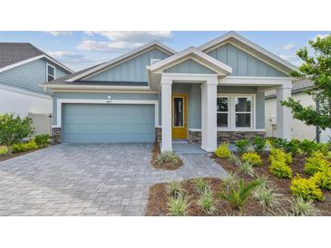 Charming single-story home with a well-manicured lawn and a stylish blue exterior and yellow door at 6063 Sacred Oak Ave, Mount Dora, FL 32757