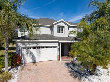 Two-story house with white garage door, landscaping, and palm trees at 13438 Davenham Pt, Orlando, FL 32832