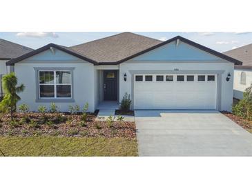 One-story home with light blue and white exterior, two-car garage, and landscaping at 486 Pine Tree Blvd, Lake Alfred, FL 33850