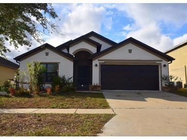 Charming single-story home with a two-car garage, manicured landscaping, and neutral color palette at 1051 Woodlark Dr, Haines City, FL 33844