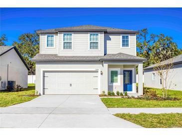 Charming two-story home with a well-manicured lawn, two-car garage, and inviting blue front door at 13465 Leaping Water Way, Astatula, FL 34705