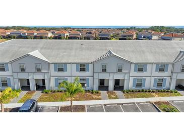 Aerial view of townhouses with gray and white exterior, and parking at 7614 Oak Spring Ln, Davenport, FL 33837
