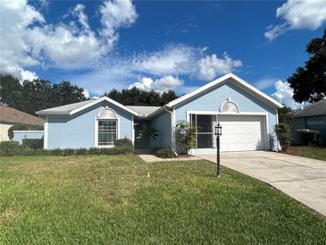 Charming single-story home features a well-manicured lawn, a two-car garage, and a lovely blue exterior at 17729 Se 114Th Ct, Summerfield, FL 34491