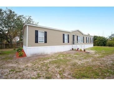Tan single-wide manufactured home with black shutters and landscaping at 3046 Crystal Hills Dr, Lakeland, FL 33801