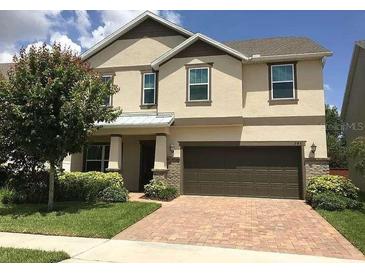 Inviting two-story home features a brick driveway, a two car garage, and manicured landscaping at 745 Marsh Reed Dr, Winter Garden, FL 34787