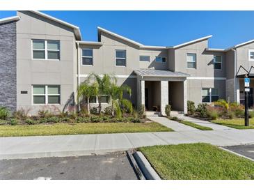Modern two-story townhome with gray siding and a covered entryway at 8989 Cabot Cliffs Dr, Davenport, FL 33896