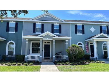 Charming townhome with a manicured lawn, classic architectural details, and a welcoming front porch at 525 Waterside Pointe Dr, Groveland, FL 34736