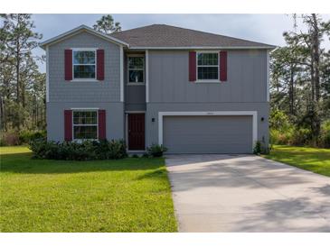 Two-story house with gray siding, red shutters, and a two-car garage at 3681 Magnolia Dr, Indian Lake Estates, FL 33855