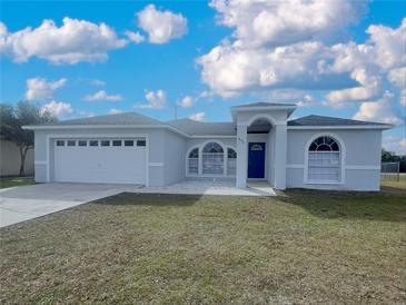 Newly built home with a two-car garage and landscaped lawn at 645 Yak Ct, Poinciana, FL 34759