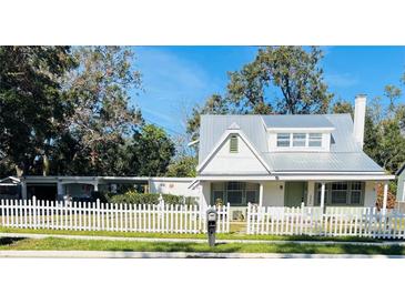 Charming cottage with metal roof, white picket fence, and landscaped yard at 415 Avenue K Ne, Winter Haven, FL 33881
