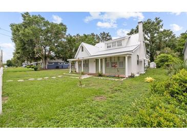 Charming home featuring a white exterior, metal roof, and a cozy front porch at 415 Avenue K Ne, Winter Haven, FL 33881