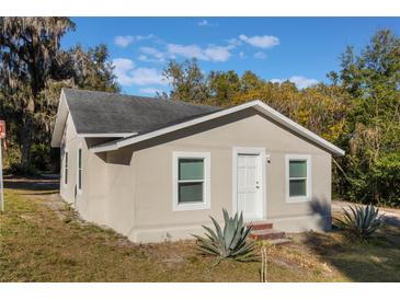 Newly renovated house exterior, featuring a light beige stucco finish and a well-maintained lawn at 521 W Voorhis Ave, Deland, FL 32720