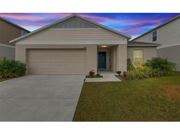Tan house with a two-car garage and landscaped lawn at 1536 Axel Cir, Winter Haven, FL 33880