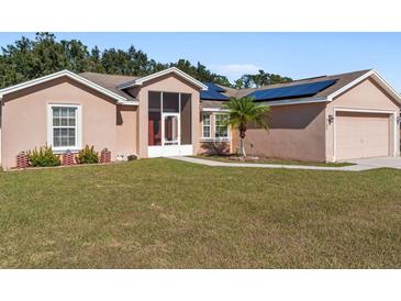 Tan house with solar panels, screened porch, and two-car garage at 3189 Winchester Estates Loop, Lakeland, FL 33810