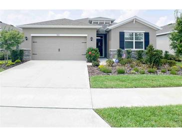Single-story house with a two-car garage and landscaped front yard at 5450 Sunshine Dr, Wildwood, FL 34785