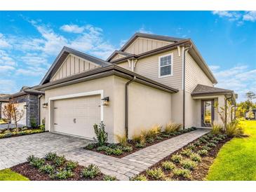 Two-story house with light beige siding, brown accents, and a paved walkway at 7748 Somersworth Dr, Kissimmee, FL 34747