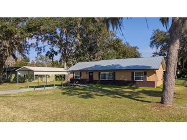 House exterior features a metal roof, carport, and landscaped lawn at 1507 Hontoon Rd, Deland, FL 32720