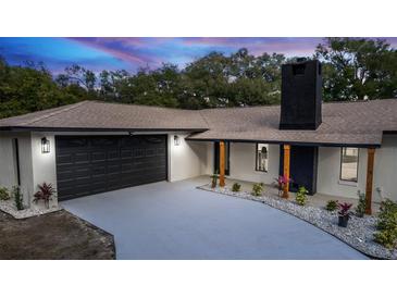 Stunning house exterior featuring a modern design, black garage door, and landscaped yard at 817 Helen Ave, Deland, FL 32720