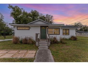 Charming white house with green door, steps, and landscaped yard at 100 Cordova Rd, Auburndale, FL 33823